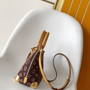 Alternative view of p690 This Alma Trunk BB st handbag draws inspiration from Louis Vuitton's 1908 archival designs, reimagining traditional elements into the Monogram Origine pattern. It features chain straps, a padlock, and metal corner pieces. Its compact shape allows for easy carrying by hand, over the shoulder, or crossbody. Dimensions: 19 x 11 x 22 cm.(Height x Width x Length)